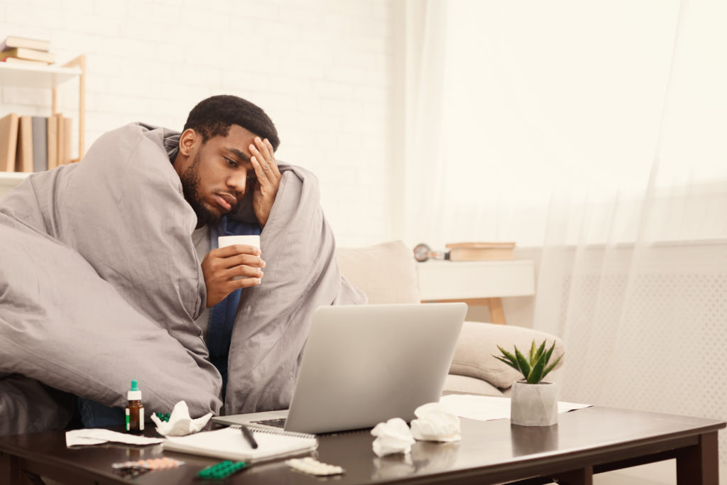 Sick man uses telehealth via laptop to talk to doctor.