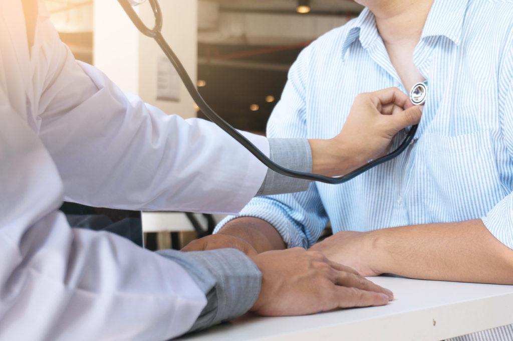 Provider checks patient's heartbeat using stethoscope.