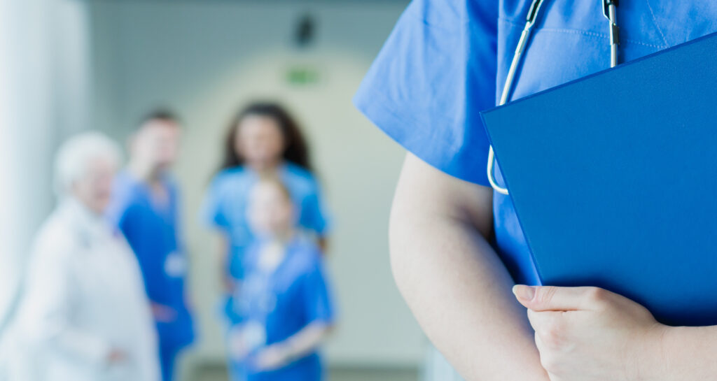 Medical group of doctors, with one physician in foreground holding a binder.